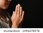 Little girl praying on dark background, closeup