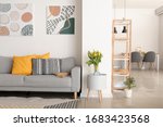 Interior of modern room with comfortable sofa and table with spring flowers