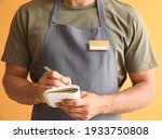 Male waiter with blank badge on color background