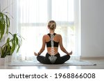 Young woman with good posture meditating at home, back view