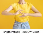 Small photo of Young deaf mute woman using sign language on color background