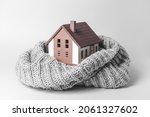 Figure of house and warm scarf on light background. Concept of heating season