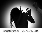 Silhouette of woman mistreated by man on dark background