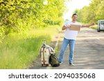 Young man with cardboard hitchhiking on road