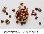 Bowl full of brown chestnuts on white background