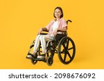 Young woman in wheelchair on color background