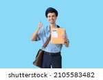 Small photo of Handsome young postman with letter showing thumb-up on color background
