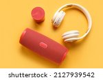 Modern wireless portable speakers and headphones on color background