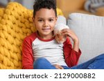 Small photo of Little African-American boy with cute guinea pig on sofa at home