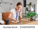 Small photo of Female notary public talking by phone while working in office