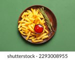 Plate with tasty french fries, rosemary and ketchup on green background