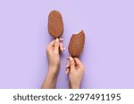 Woman holding tasty chocolate covered ice cream on lilac background