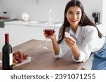 Young woman with glass of wine and cheese in kitchen