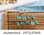 When lambo written in cookies drying on a metal grill on a wooden board with blue icing