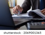 Small photo of Businessman in suit hand stamping rubber stamp on document in folder with laptop computer on the desk at office. Authorized allowance permission approval concept.
