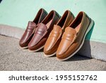 Two pairs of fine genuine leather loafers against a colorful summer color wall.
