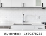 Detail shot of a modern kitchen sink with white cabinets, granite and subway tile.