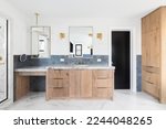 Small photo of A luxurious bathroom with a wood vanity cabinet, blue tiles on the walls, gold accented lights and mirrors, and a large walk-in shower lined with marble tiles.
