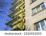 Small photo of Thermal insulation of the facade of a multi storey apartment building with thick rock mineral wool slabs using scaffold, blue sky background