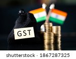 Small photo of Bag with GST sticker in front of the stack of Coins and Indian flag as background - Concept goods and service indirect tax collection in India.