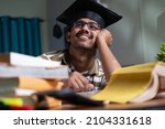 Small photo of young student dreaming about graduation while studing book or preparing for examination at home - concept of daydreaming and future career goal and education.