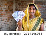 Small photo of Happy smiling Indian woman with currency notes looking at camera - concept of daily wager or construction woker earnings, banking and financial