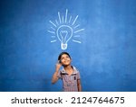 Small photo of excited Kid with suddenly got or pop up idea expression under light doodle on blue background - concept of child found solution, creativity and brainstorm.