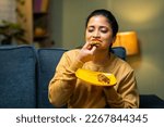 medium shot of girl enjoys eating tasty pizza by closing eyes at home on sofa - concept of yummy food, excitement and emotion or expression.