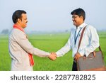 Small photo of Happy village farmer greeting banker by hand shake by showing paddy field - concept of financial support, service and agriculture investment or banking.