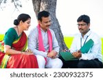 Small photo of Indian banker explaining agri loan scheme to farmer village couple while sitting on farmland - concept of expertise, banking support and investment consultation