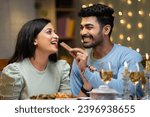 Small photo of Happy boyfriend giving chocolate byte to girl friend during candle light dinner at restaurant - concept of valentine's day celebration, romantic couples and intimacy.