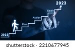 Small photo of New Year 2023 with plan, action and goals.Businessman pointing to the growing plan of successful business in 2023 year and a figure climbs the ladder of success.
