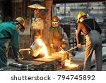 Group of workers in a foundry at the melting furnace - production of steel castings in an industrial company 