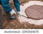 Small photo of A worker opens a well hatch with a pry bar. Troubleshooting, checking septic tanks.