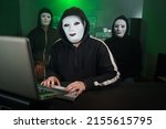 Small photo of Team of Masked Hackers Using Computer to inflict Data Breach Attack on Government Servers. Anonymous Digital Crime