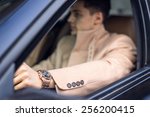 Handsome stylish male driving the car, focus on the watch (foreground). Natural light
