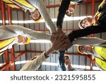 Small photo of Group of male and female factory labor join hands together after finish meeting. Everyone wearing safety uniform and helmet. Workers working in the metal sheet factory. Bottom View