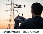 Man operating drone close to the electrical wire/ man holding remote control drones / drone controller. Drone safety. Man operating drone / man holding remote control drones.