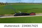 Small photo of A Drone View of a Restored Steam Locomotive and Caboose, Going Over a Small Bridge, Blowing Smoke, on a Sunny Day