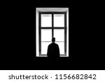 A man's silhouette in front of the window. Black and white. Concept of loneliness and isolation. 