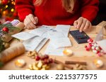 Woman sitting at the table, checking her bills after buying everything for Christmas. Winter holidays shopping, expensive time of the year