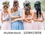 three bridesmaids in powdery dresses transformers and wreaths on the head embrace the bride in a blue dress