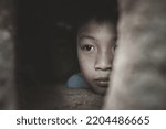 Small photo of Closeup poor boy peeking out of a dilapidated house, Concept of assistance to the poor, human rights.