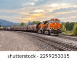 Small photo of freight train with colorful sunset transporting cargo close to Whitefish, Montana in springtime