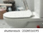 Dirty transparent calcified shower glass door with limescale, plaque from soap and hard water, view of bathroom with toilet on background. Cleaning company concept. Housework concept.