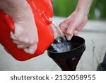 Small photo of Gasoline transfusion from a plastic gas tank through a plastic funnel. Danger of ignition of fuel from static electricity during pouring.