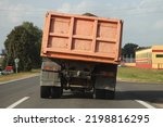 Heavy overloaded dump truck with lurch carries sand on a European countryside asphalt road at summer day