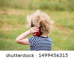 Young child wearing noise blocking headphones at outdoor concert, preventing hearing loss at young age concept.
