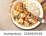Small photo of Closeup of Blanquette de poulet, French chicken stew with carrots, mushrooms, onion. Simmered in a white stock and served in a sauce enriched with cream, with white rice in a white plate.