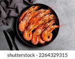 Top view of giant argentinian red prawns, grilled. Black plate. Dark grey background.